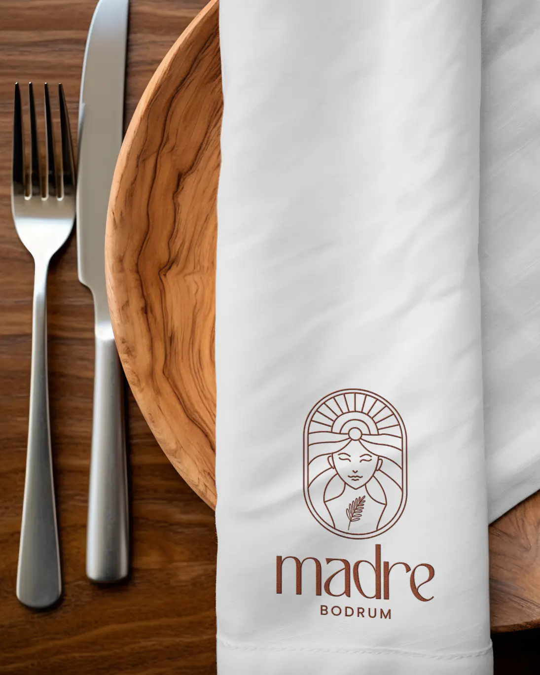 Madre Bodrum logo on a napkin, next to a wooden plate and cutlery